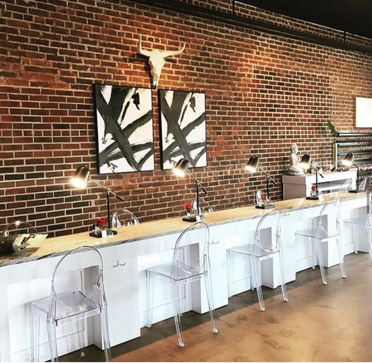 Inside the flagship salon — white service bar, ghost chairs, and exposed brick