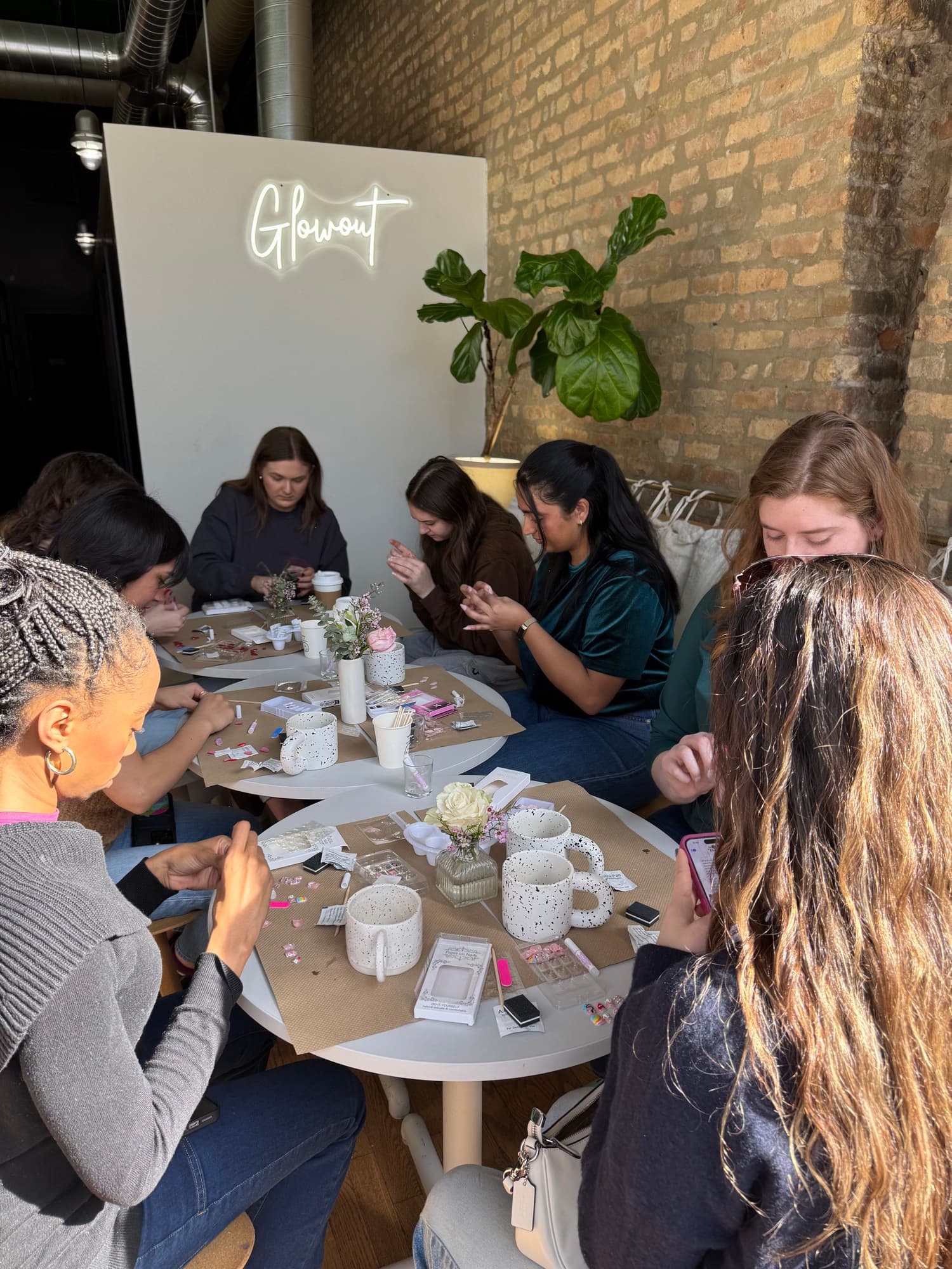 Guests around tables at a hosted workshop, neon script glowing behind them