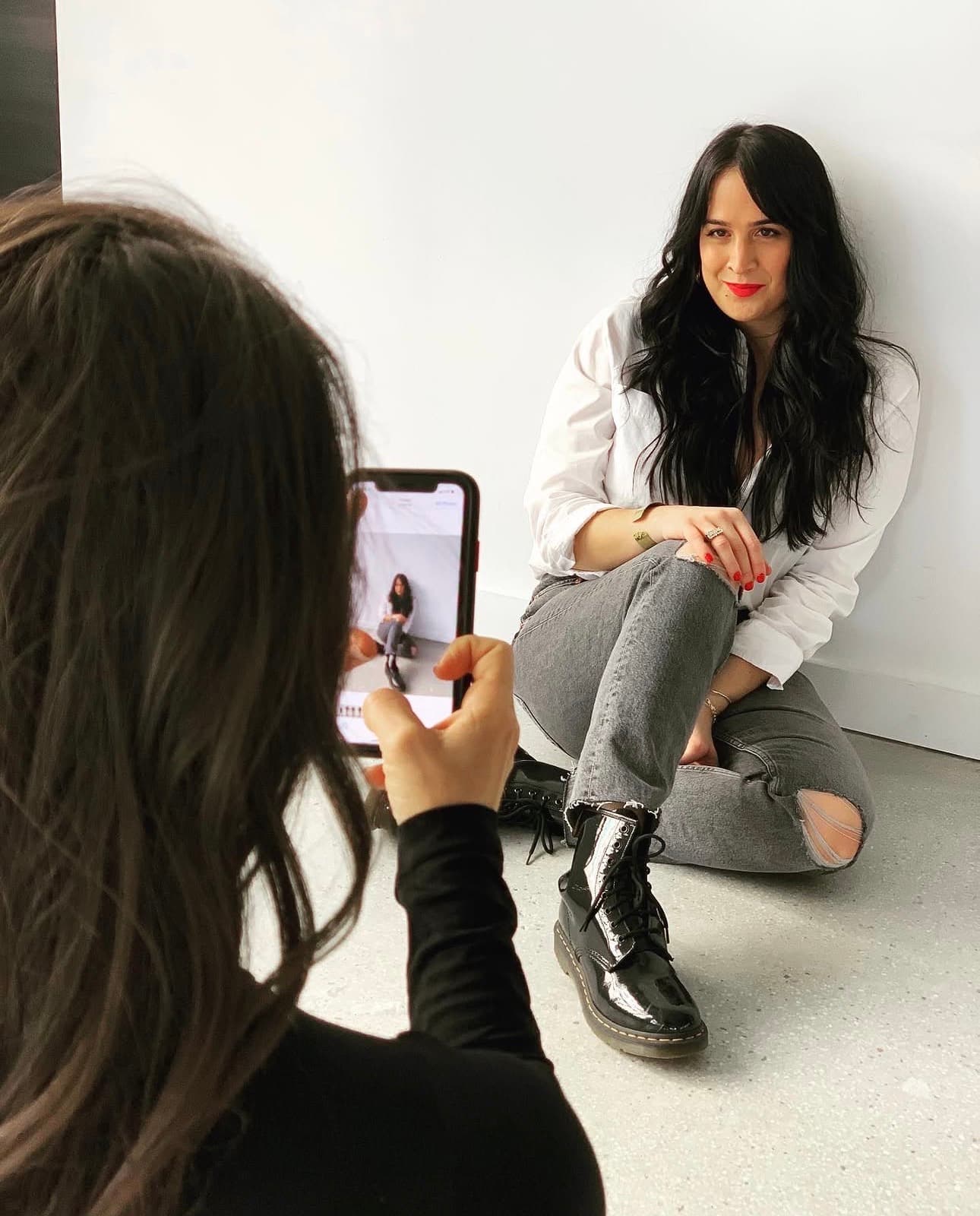 A brand photoshoot in progress — photographer framing a founder against a white studio wall